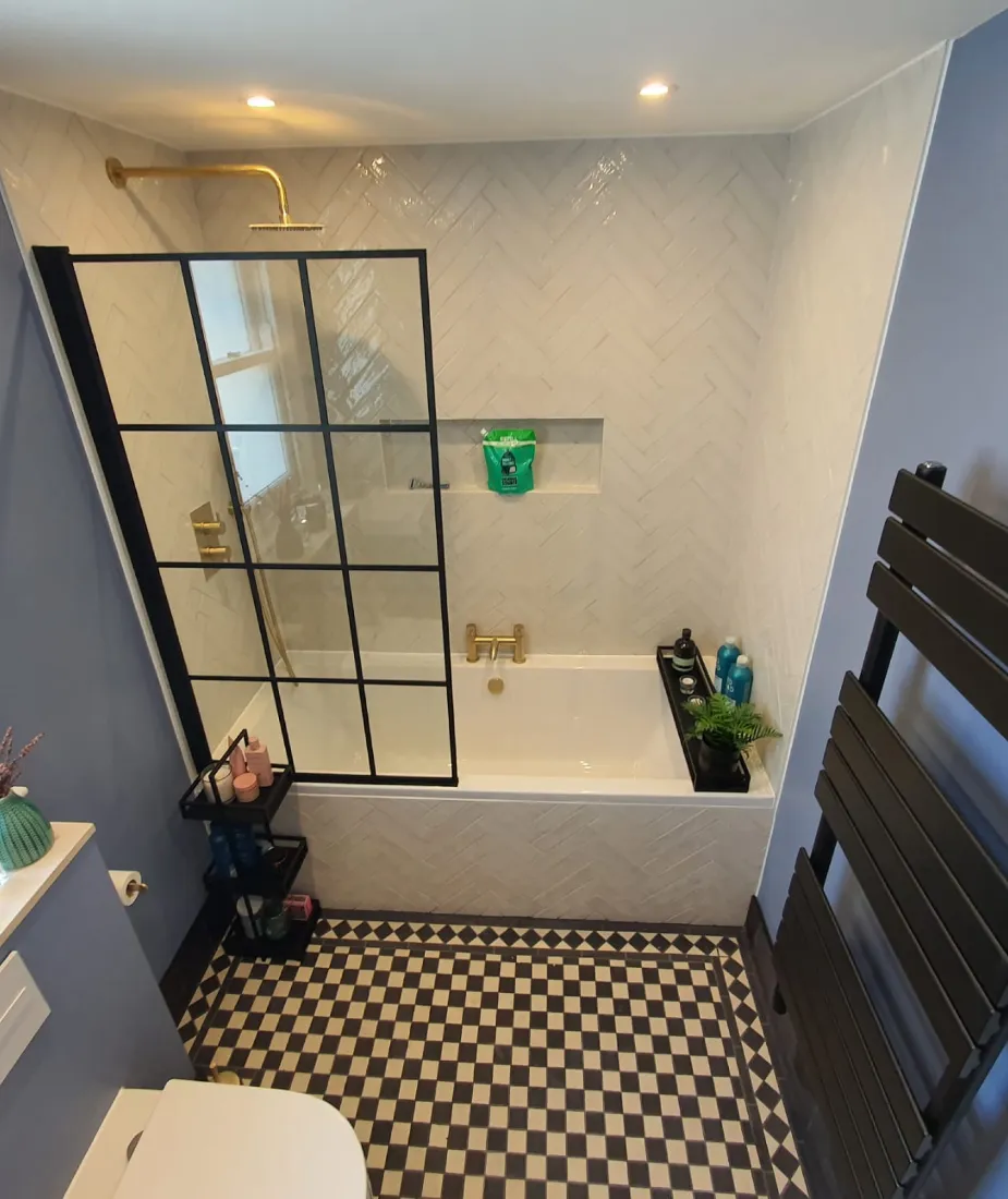 Bathroom fitted by Boiler & Heating Care with a black-framed shower screen, brass taps and checkerboard floor
